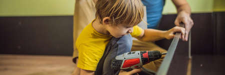 Father and son assembling furniture. Boy helping his dad at home. Happy Family concept. BANNER, LONG FORMATの写真素材