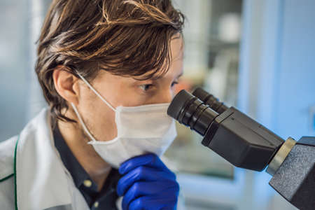 Portrait of caucasian male chemist scientific researcher using microscope in the laboratory...