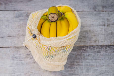 Banana in a reusable bag on a stylish wooden kitchen surface. Zero waste concept, plastic free...