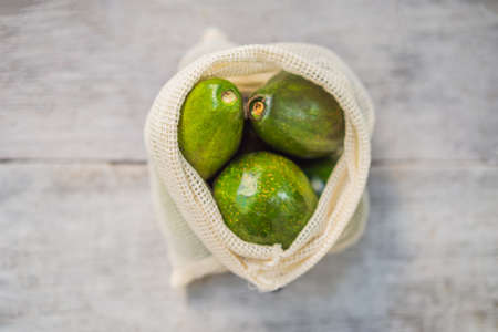 Avocado in a reusable bag on a stylish wooden kitchen surface. Zero waste concept, plastic free...