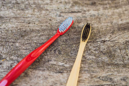 Natural bamboo toothbrush and plastic toothbrush. rustic background. sustainable lifestyle concept....