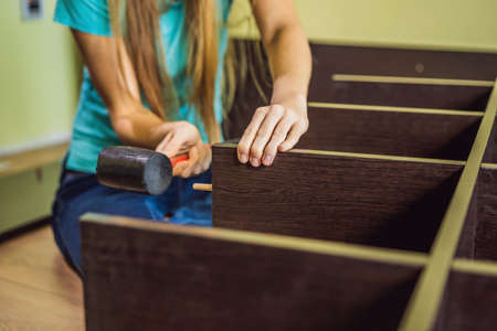 Caucasian woman using screwdriver for assembling furniture.
