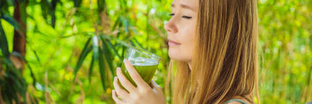 Young woman drinks Celery Juice, Healthy Drink, bunch of celery on a wooden background BANNER, LONG FORMATの写真素材