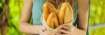 Reusable grocery bags with bread in the hands of a young woman. Zero waste shopping. Zero waste...