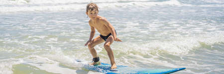 Healthy young boy learning to surf in the sea or ocean BANNER, LONG FORMATの写真素材