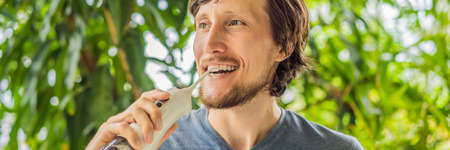 Young man uses an oral irrigator to brush his teeth BANNER, LONG FORMAT
