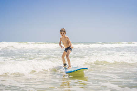 Healthy young boy learning to surf in the sea or oceanの写真素材