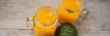 Orange juice and oranges with green peel on a wooden background. BANNER, LONG FORMAT