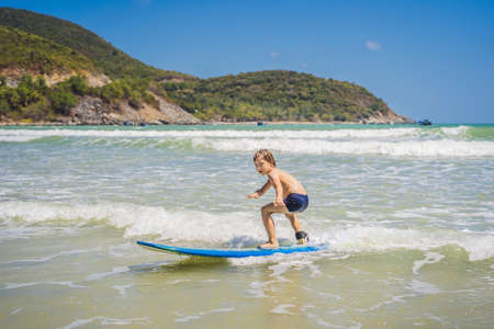 Healthy young boy learning to surf in the sea or ocean.の写真素材