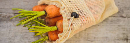 Carrot in a reusable bag on a stylish wooden kitchen surface. Zero waste concept BANNER, LONG FORMATの写真素材