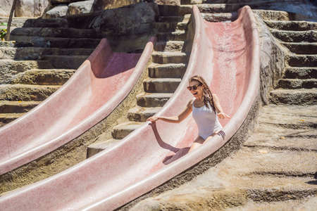 Woman on a stone water slide in a water park. Aqua park, Girl slide down on water slide