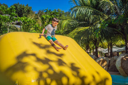 Cute boy runs an inflatable obstacle course in the pool.の写真素材