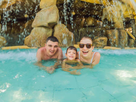 Happy family on holidays swimming with fun in waterfall pool. Active lifestyle, people outdoor travel activity on summer vacation on tropical islandの写真素材