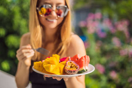 Young woman resting on a balcony with a plate of fruit. life-work balance, relaxation healthy quality living lifestyle in summer holiday vacation of freelancer woman take it easy resting in resort hotel balcony having peace of mindの写真素材