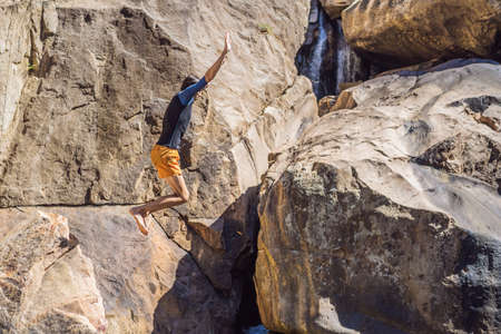 A man jumping from a cliff into a riverの写真素材