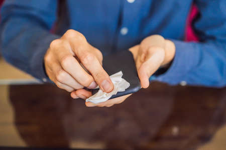 Man cleaning smartphone screen with alcohol or sanitizer. Concept of Cleaning dirty screen phone for disease prevention from bacteria. coronavirus covid 19の写真素材