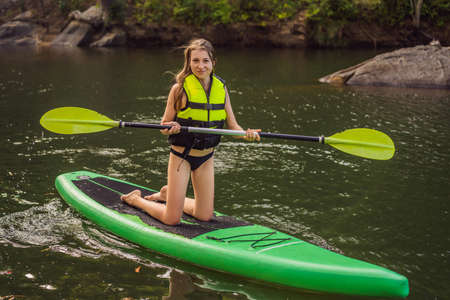 SUP Stand up paddle board woman paddle boarding on lake standing happy on paddleboard on blue water....