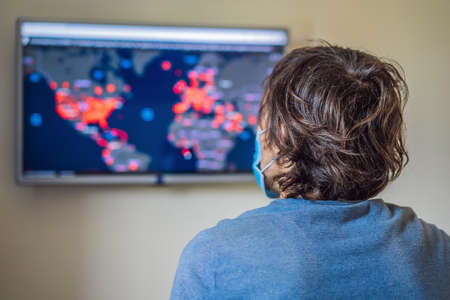Young man checks coronavirus sars-cov-2 covid-19 global cases situation online. Coronavirus outbreak...