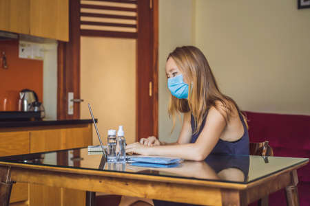 Coronavirus. Young business woman working from home wearing protective mask. Business woman in...