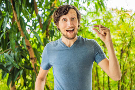 Man placing a bite plate in his mouth to protect his teeth at night from grinding caused by bruxismの写真素材