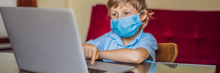 Boy studying online at home using laptop in medical masks to protect against coronovirus. Studying during quarantine. Global pandemic covid19 virus BANNER, LONG FORMATの写真素材