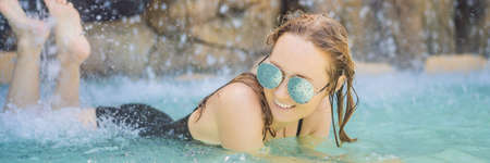 Young joyful woman under the water stream, pool, day spa, hot springs BANNER, LONG FORMAT