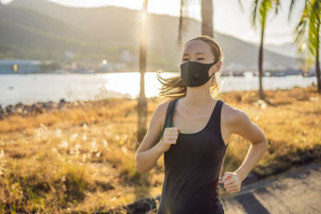 Young attractive woman in a black medical mask prepares for a jogging in countrysideの写真素材