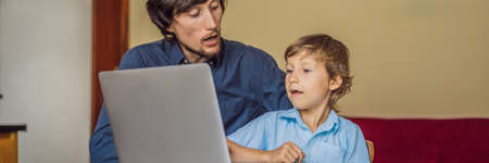 Boy studying online at home using laptop. Father helps him learn. Studying during quarantine. Global...