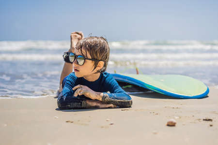 Young surfer, happy young boy at the beach with surfboard.の写真素材