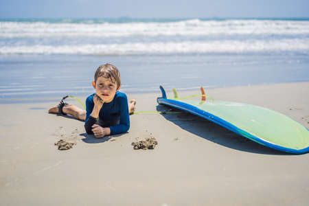 Young surfer, happy young boy at the beach with surfboard