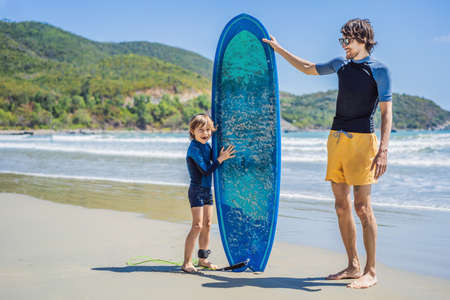 Father or instructor teaching his son how to surf in the sea on vacation or holiday. Travel and...