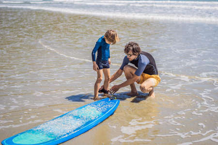 Father or instructor teaching his son how to surf in the sea on vacation or holiday. Travel and...