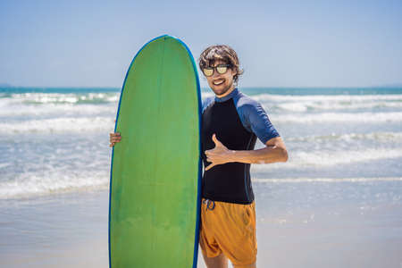 Surfer holding a surf board on beachの写真素材