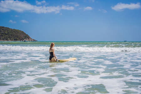Beautiful young woman ride wave. Sporty surfer woman surfing on the background of blue sky, clouds and transparent waves. Outdoor Activeの写真素材