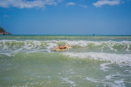 Beautiful young woman ride wave. Sporty surfer woman surfing on the background of blue sky, clouds...