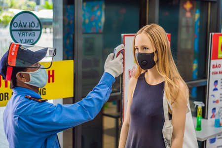 Vietnam, Nha Trang, 15.04.2020: Medical staff are checking the temperature of woman. Before entering the area with an epidemic Covid-19のeditorial素材