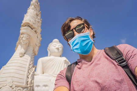 Man tourist in medical mask on background of Big Buddha statue Was built on a high hilltop of Phuket Thailand Can be seen from a distance Tourists fear the 2019-ncov virus. Medical masked touristsの写真素材