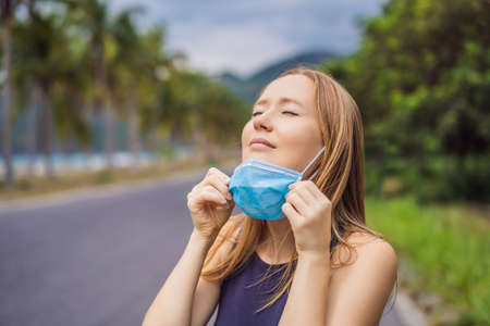 Quarantine is over concept. Woman taking off mask outdoor. We are safe. Coronavirus ended. We won. No more quarantine. Breathe deep. Take off the mask. Coronavirus is overの写真素材