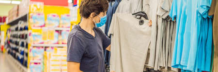 Man in a clothing store in a medical mask because of a coronovirus. Quarantine is over, now you can...
