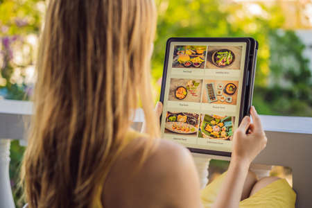 Young woman orders food for lunch online using Tabletの写真素材