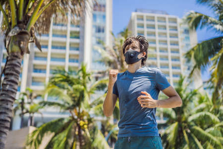 Man runner wearing medical mask. Running in the city against the backdrop of the city. Coronavirus...