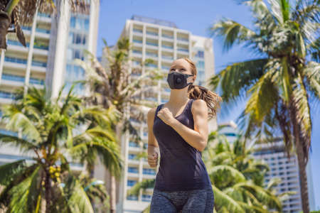 Woman runner wearing medical mask. Running in the city against the backdrop of the city. Coronavirus...