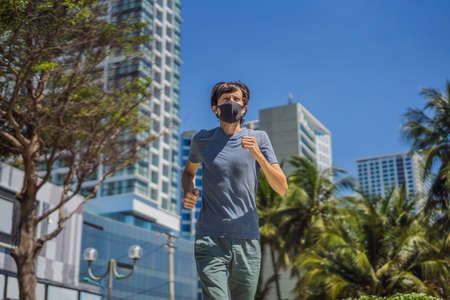 Man runner wearing medical mask. Running in the city against the backdrop of the city. Coronavirus...