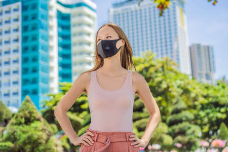 Fashionable black medical mask with filter in the city. Coronavirus 2019-ncov epidemic concept. Woman in a black medical mask. Portrait of a woman with expressive eyes during a virus or disease epidemic.の写真素材