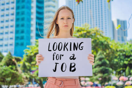 Woman holds a poster LOOKING FOR A JOB Hand written text - lettering isolated on white. Coronovirus COVID 19 conceptの写真素材