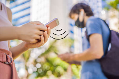 contact tracing app COVID-19 Pandemic Coronavirus Mobile Application - people Wearing Face Mask Using Smart Phone App in City Street to Aid Contact Tracing in Response to the 2019-20 Coronavirus Pandemicの写真素材