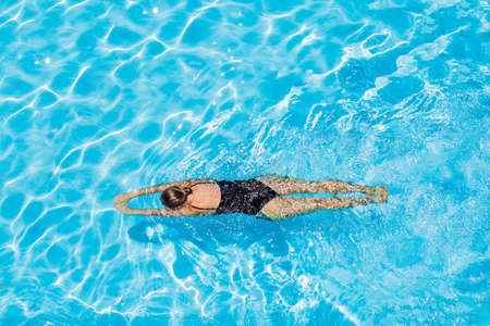 woman with black swimsuit swimming on a blue water poolの写真素材