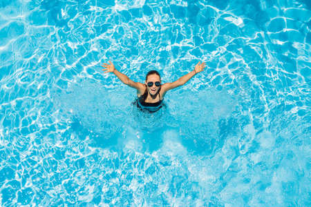 Woman in sunglasses swims in the pool