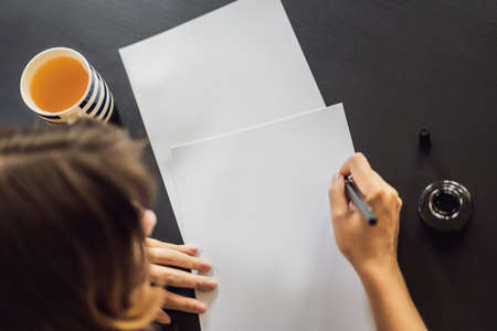 MOCKUP, SCENE CREATOR Calligrapher Young Woman writes phrase on white paper. Inscribing ornamental decorated letters. Calligraphy, graphic design, lettering, handwriting, creation concept.の写真素材