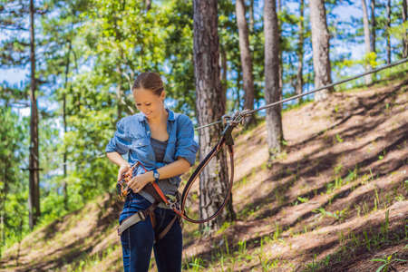 Young attractive woman in adventure rope park in safety equipment.